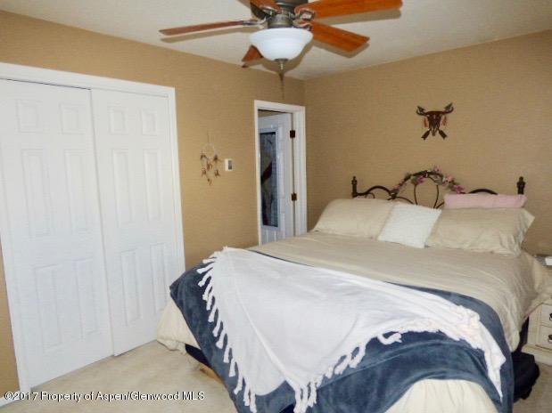 410 Evergreen Drive Rifle, CO 81650 - Photo 8 of 14 a bedroom with a bed and a chandelier