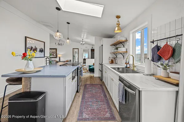 a kitchen with stainless steel appliances granite countertop a sink dishwasher and a stove with wooden floor