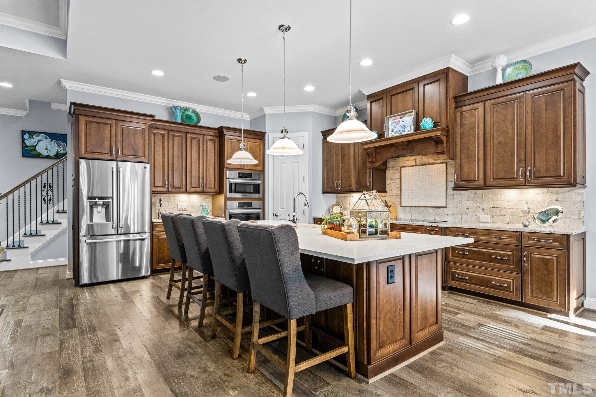 384 Colonial Ridge Drive Pittsboro, NC 27312 - Photo 9 of 47 a kitchen with stainless steel appliances granite countertop a stove a refrigerator a kitchen island a sink cabinets and wooden floor