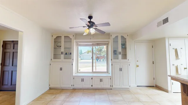 a view of an empty room with window chandelier fan