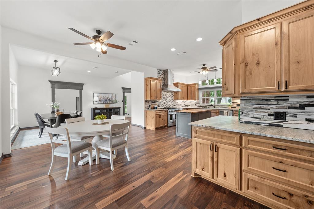 3091 Rockbridge Road McGregor, TX 76657 - Photo 4 of 40 a kitchen with stainless steel appliances kitchen island granite countertop a stove a sink and white cabinets with wooden floor