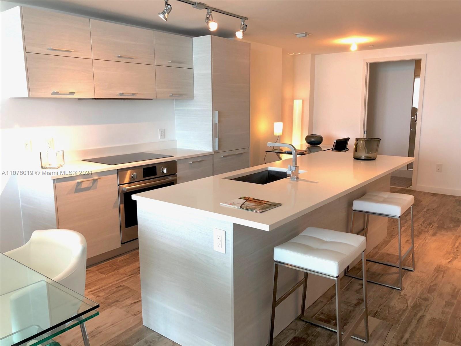 650 Northeast 32nd Street, Unit 4103 Miami, FL 33137 - Photo 7 of 44 a kitchen with a dining table chairs and a refrigerator