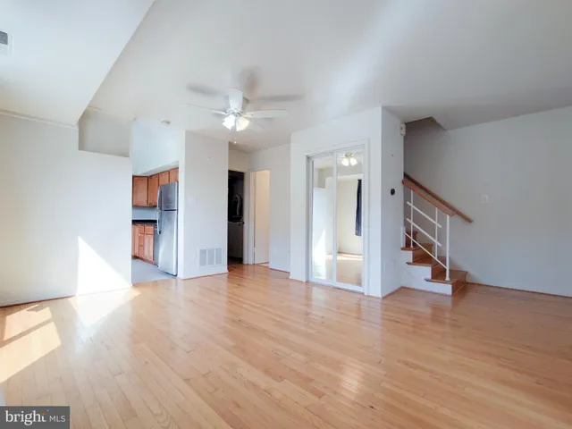a view of a hallway with wooden floor and a kitchen space with a kitchen