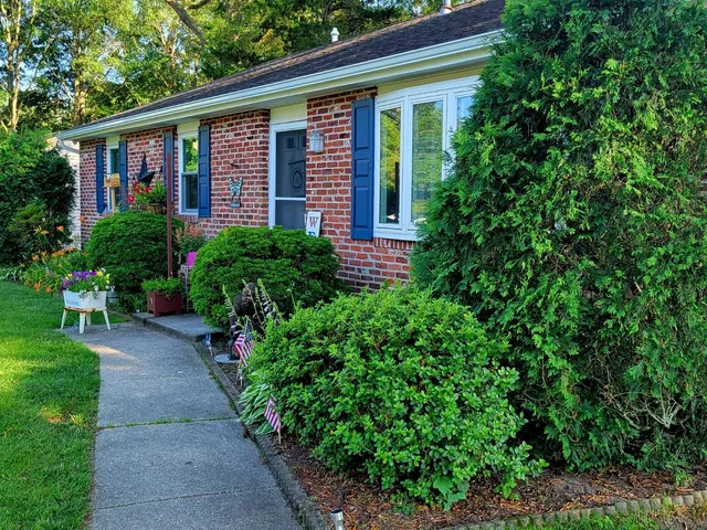 a view of brick house with a yard and potted plants