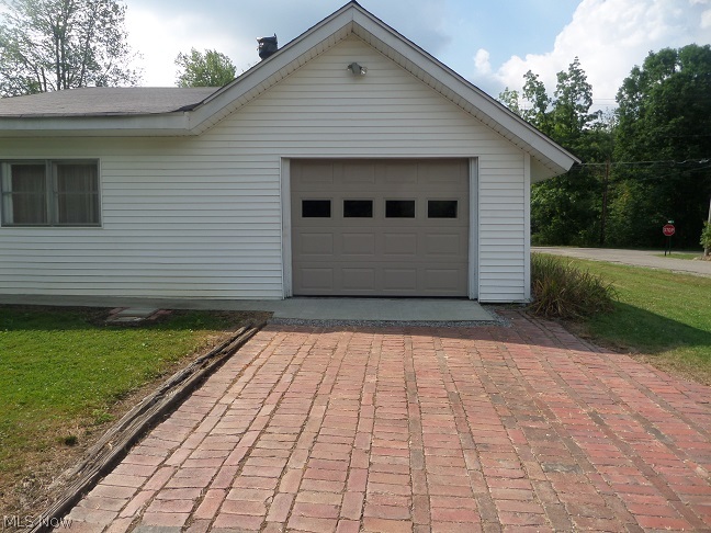 Brick driveway leads to attached garage.