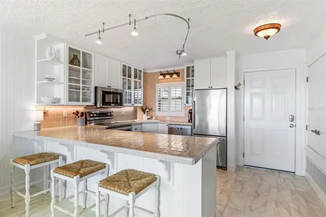 a kitchen with granite countertop a table chairs refrigerator and microwave