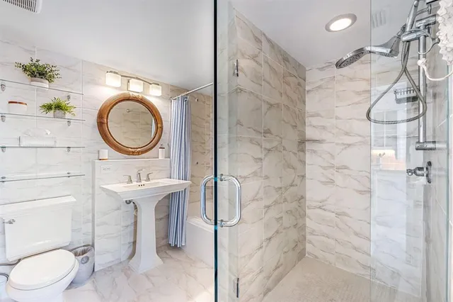 a bathroom with a toilet sink vanity granite and a shower