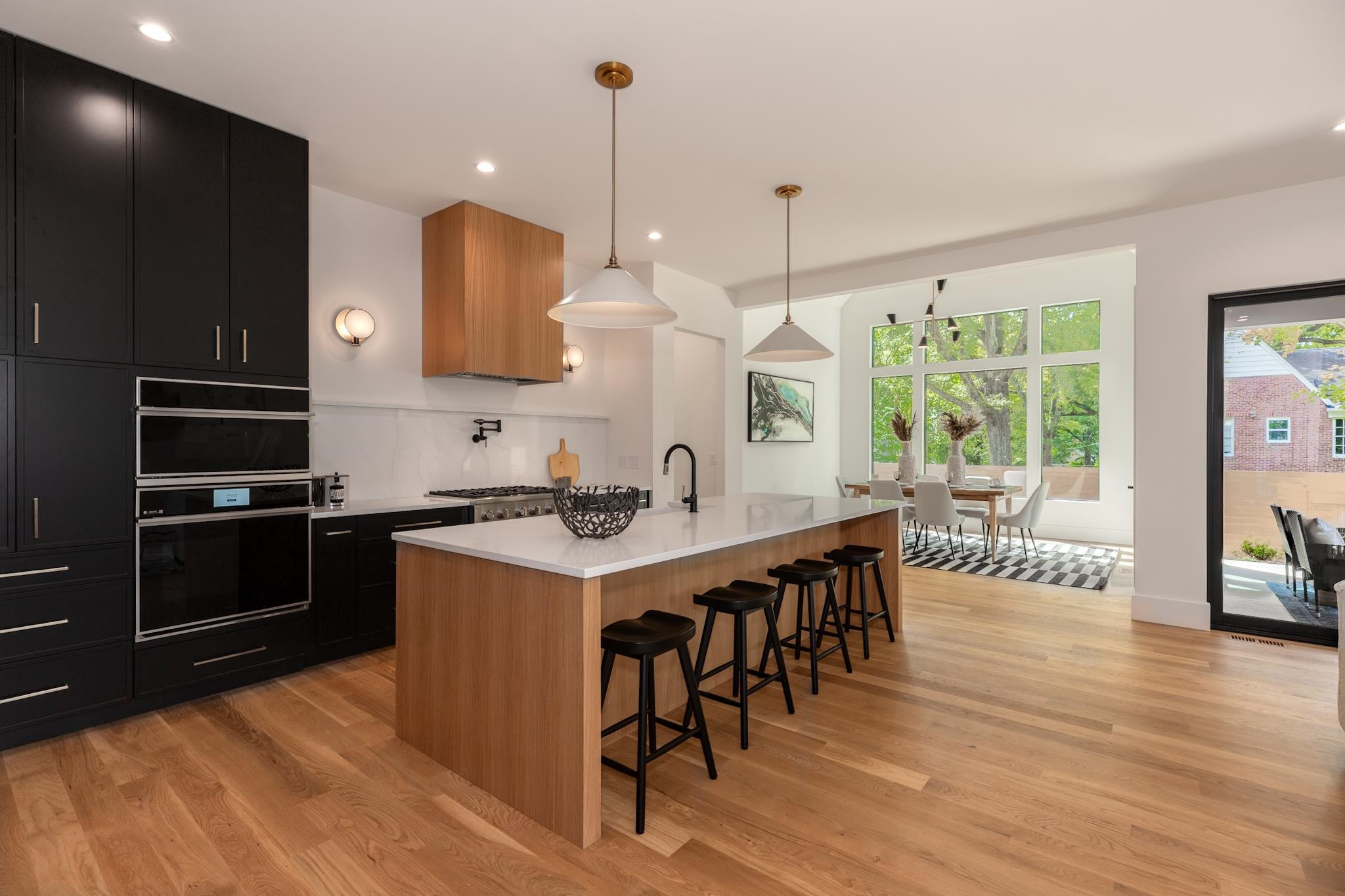 807 Chamberlain Street Raleigh, NC 27607 - Photo 27 of 40 a kitchen with stainless steel appliances granite countertop a stove a sink a microwave a dining table and chairs with wooden floor