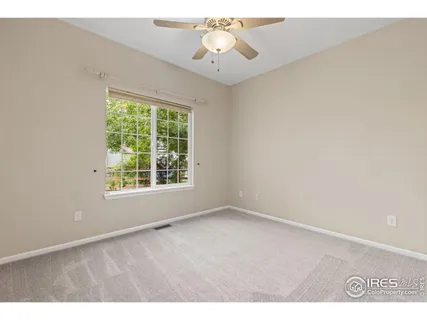 a view of an empty room with window and chandelier fan