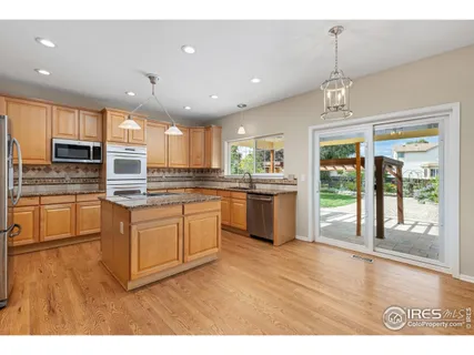 a kitchen with stainless steel appliances granite countertop a refrigerator a sink dishwasher a oven with white cabinets and wooden floor