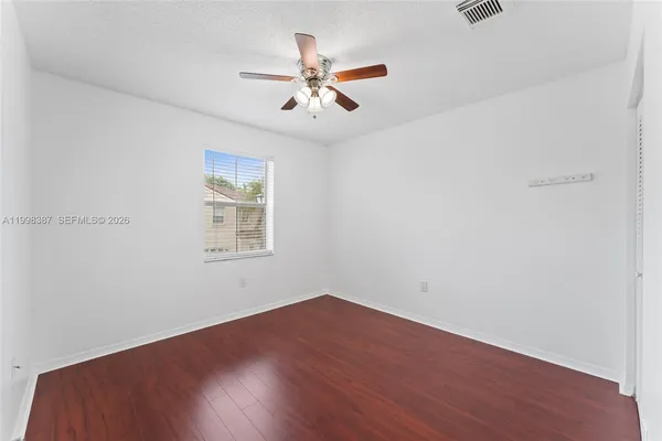 an empty room with wooden floor and ceiling fan