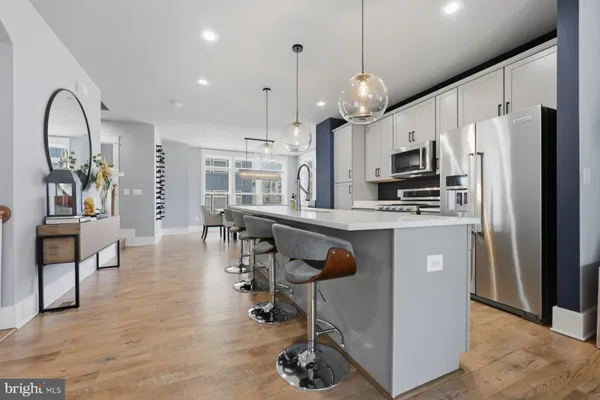 a kitchen with stainless steel appliances granite countertop a refrigerator a stove a sink a dining table and chairs with wooden floor