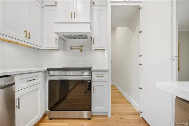 a kitchen with stainless steel appliances granite countertop a refrigerator a oven and a sink with wooden floor