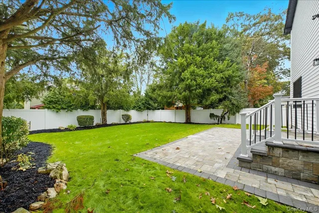a backyard of a house with plants and large tree