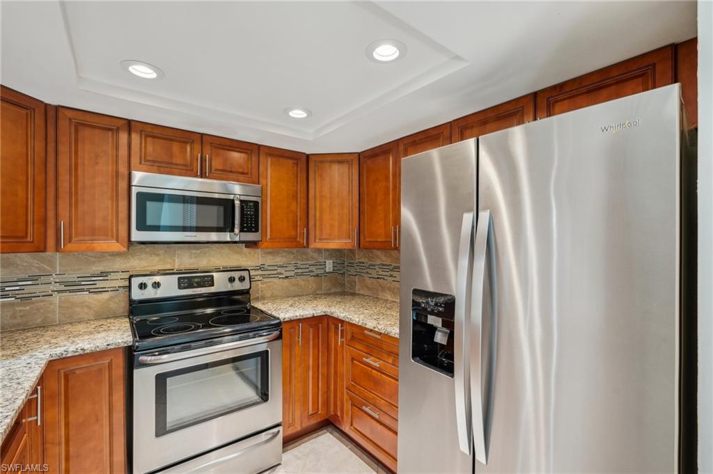 13345 Broadhurst Loop Fort Myers, FL 33919 - Photo 14 of 33 Kitchen featuring appliances with stainless steel finishes, recessed lighting, light stone countertops, decorative backsplash, and a tray ceiling