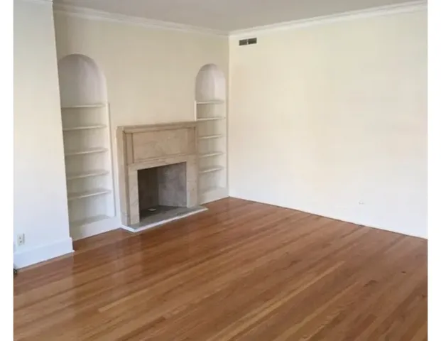 a view of empty room with wooden floor and fireplace