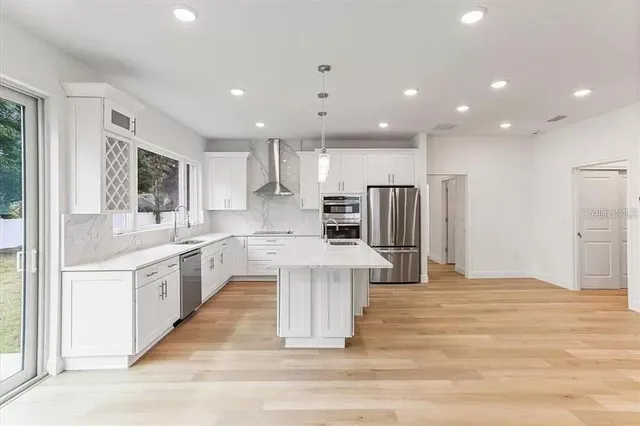 a large white kitchen with kitchen island a sink a center island stainless steel appliances and a cabinets