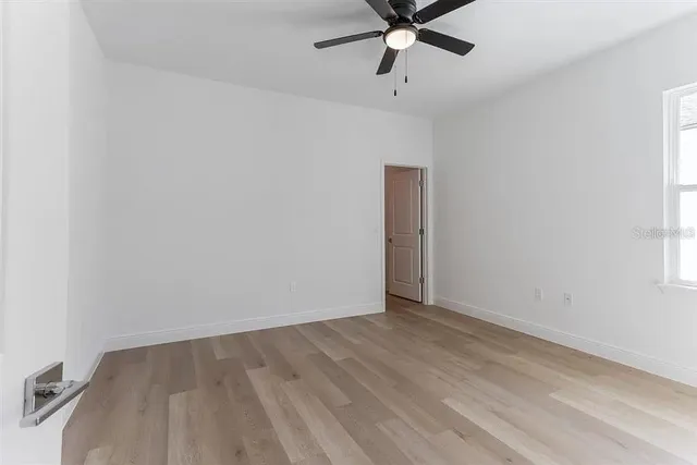 an empty room with a window and a fan