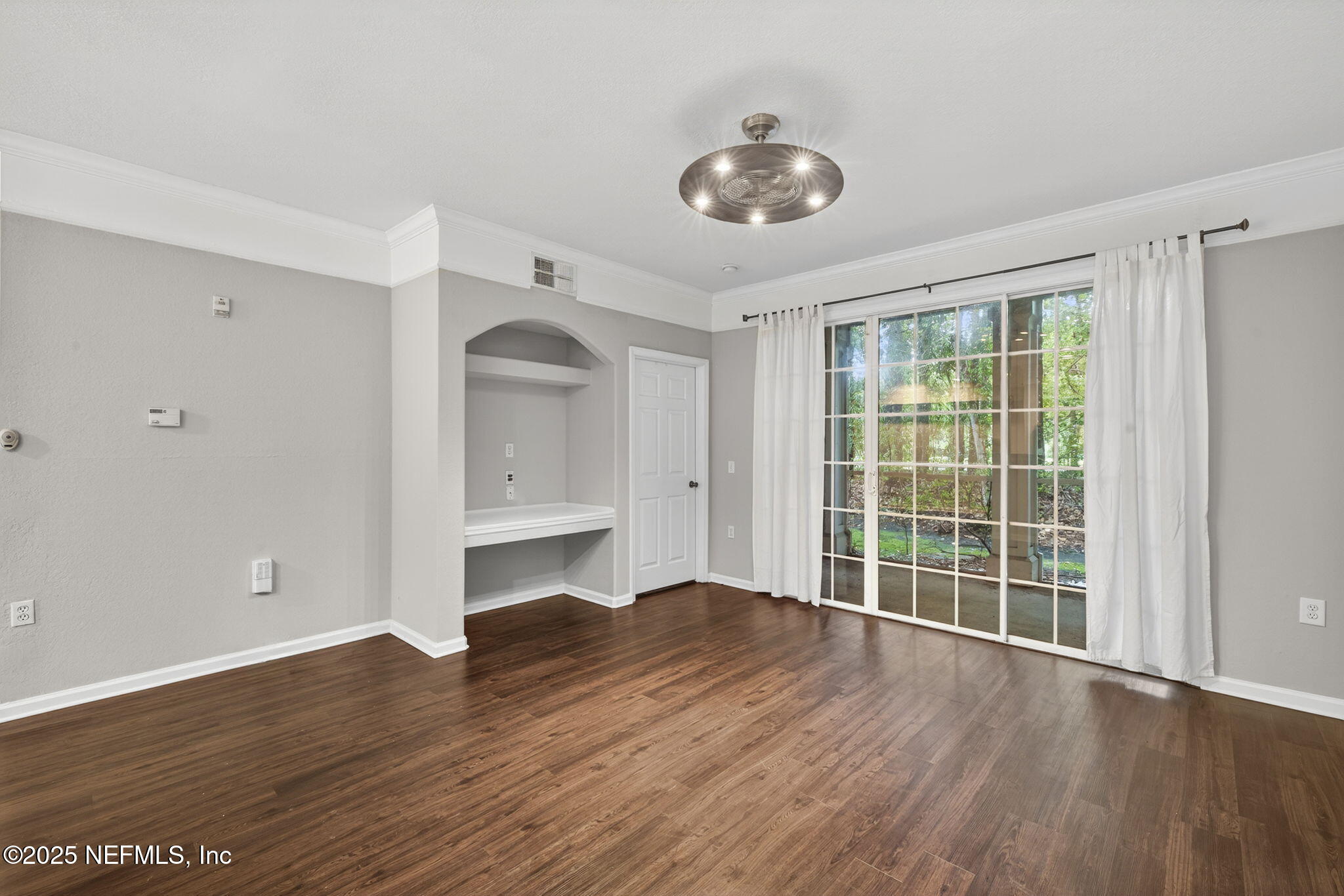 a view of an empty room with wooden floor and a window