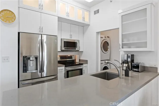 a kitchen with stainless steel appliances a sink a stove a microwave a refrigerator a counter space and cabinets