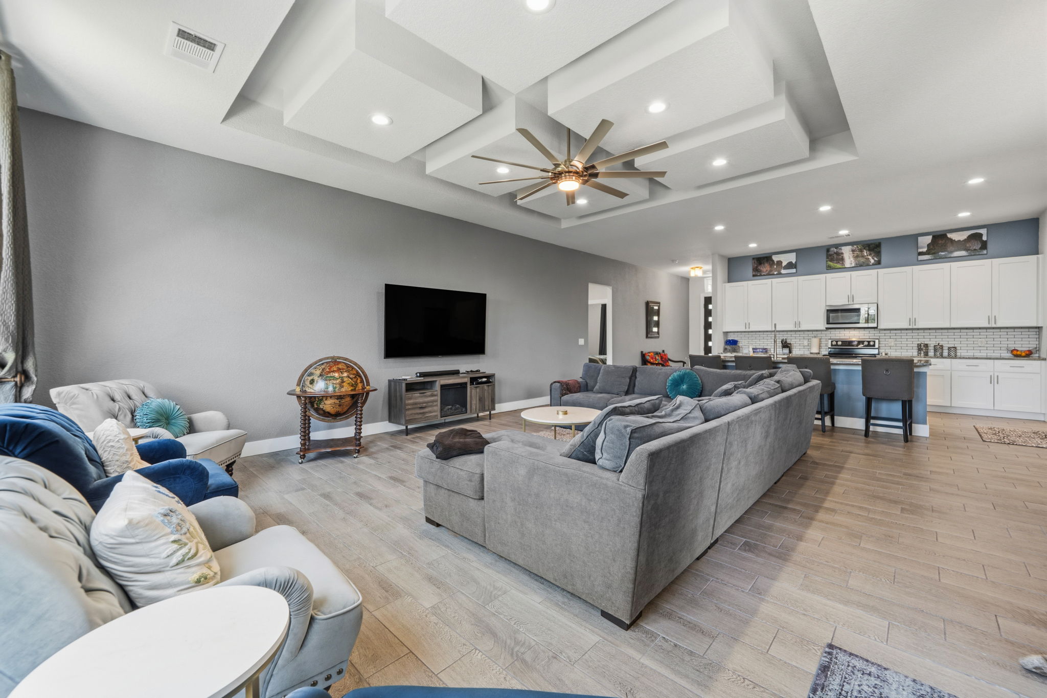 18605 Masters Cove Point Venture, TX 78645 - Photo 12 of 40 Open-concept living space featuring wood-finish flooring, a multi-level tray ceiling with recessed lighting, and a modern ceiling fan