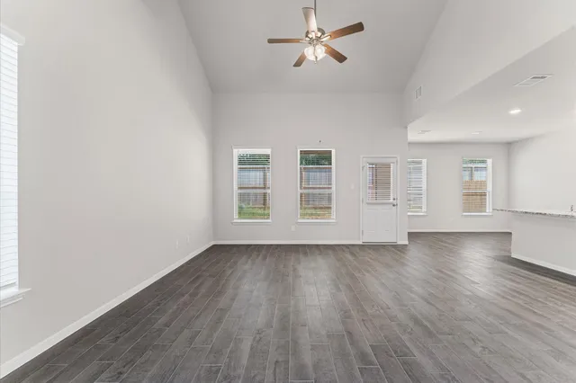 a view of empty room with wooden floor and ceiling fan