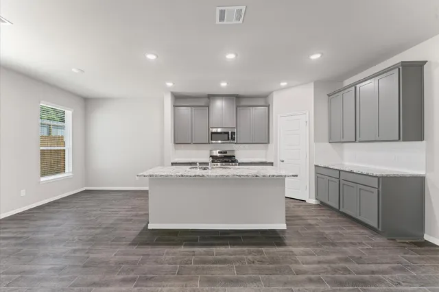 a view of kitchen with granite countertop stove top oven and sink