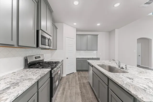 a kitchen with stainless steel appliances granite countertop a sink stove and cabinets