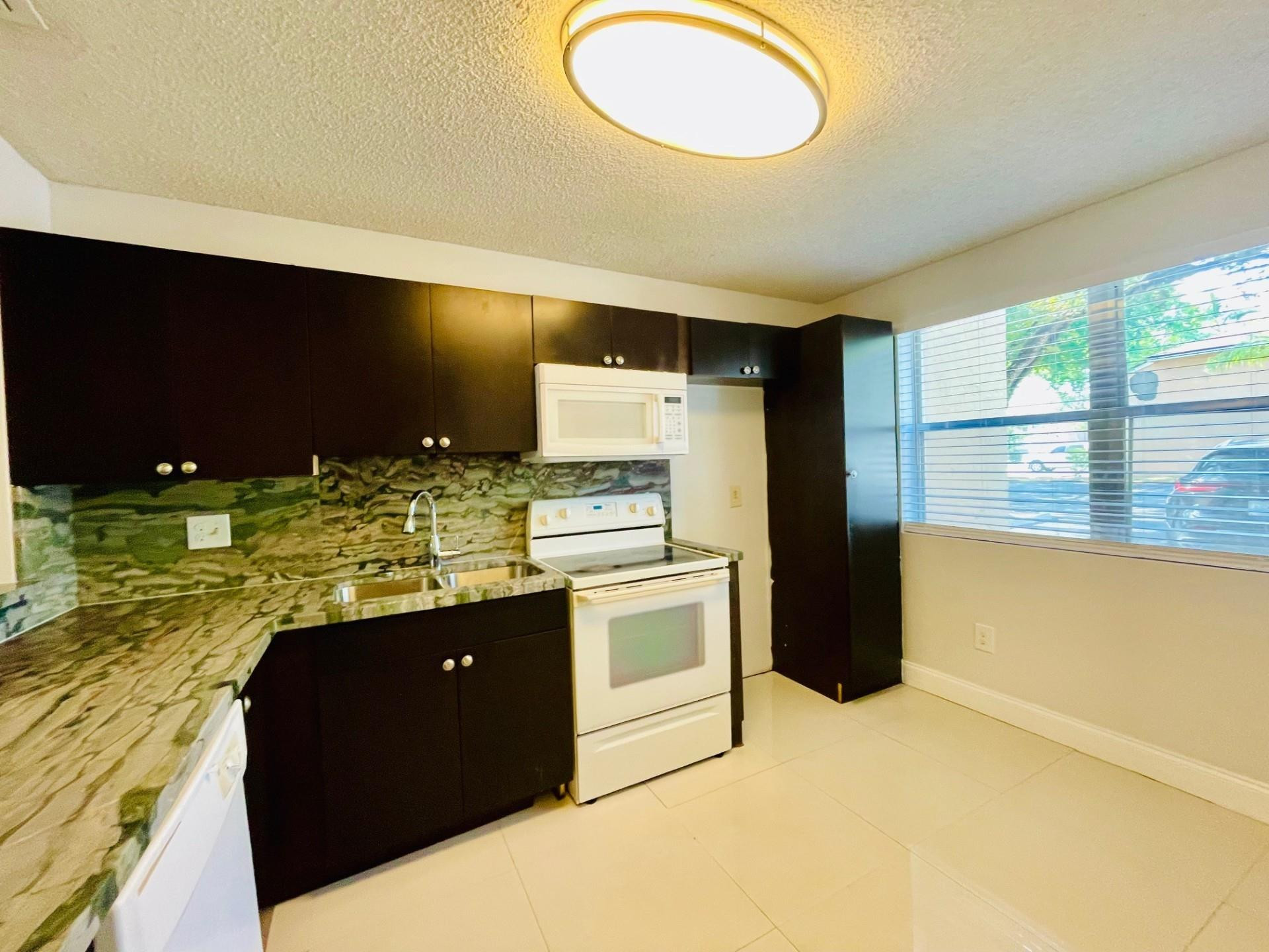 2201 Southwest 80th Terrace, Unit 2201 Miramar, FL 33025 - Photo 5 of 26 a kitchen with stainless steel appliances granite countertop a sink a stove and a refrigerator