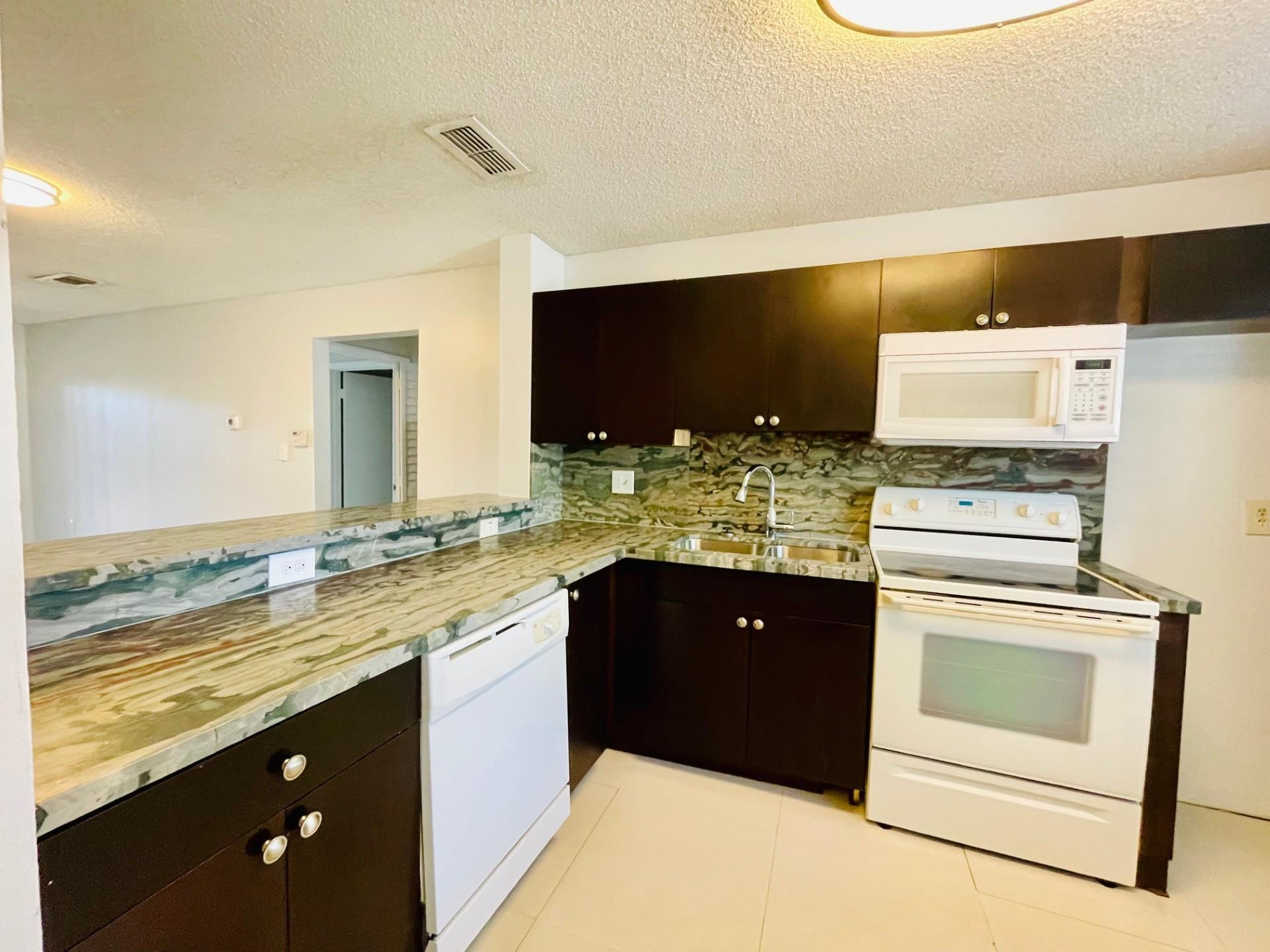 2201 Southwest 80th Terrace, Unit 2201 Miramar, FL 33025 - Photo 7 of 26 a kitchen with stainless steel appliances granite countertop a sink stove and refrigerator