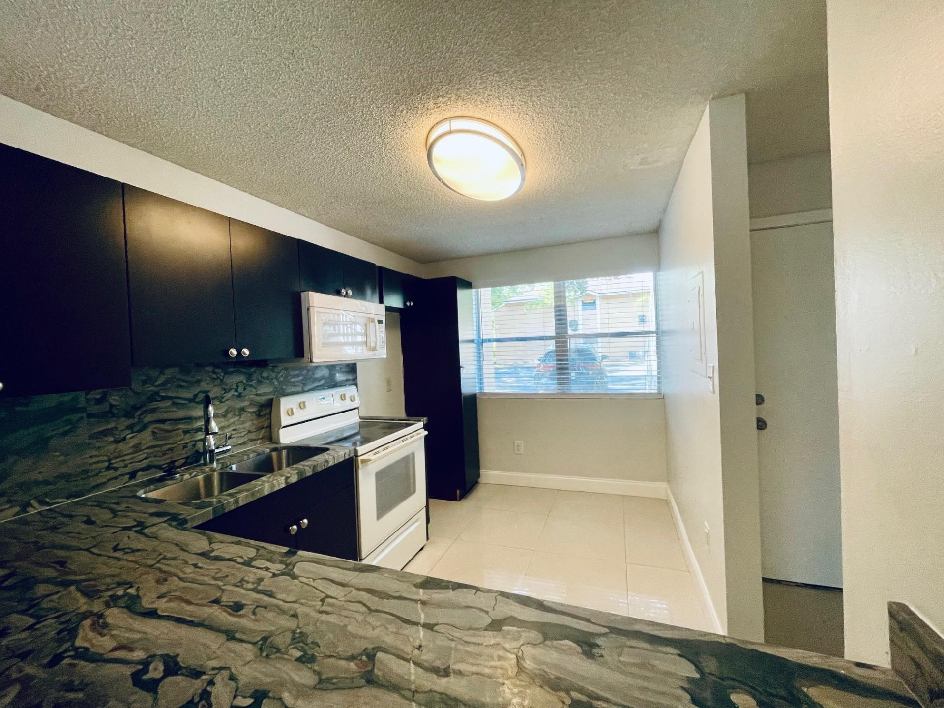 2201 Southwest 80th Terrace, Unit 2201 Miramar, FL 33025 - Photo 8 of 26 a kitchen with granite countertop a stove and a sink