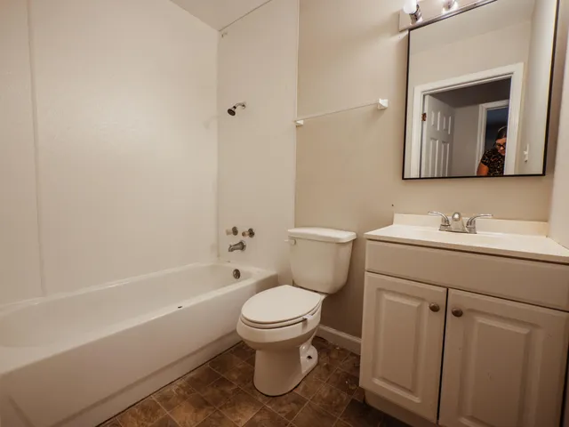 a bathroom with a toilet a sink a mirror a bathtub and vanity