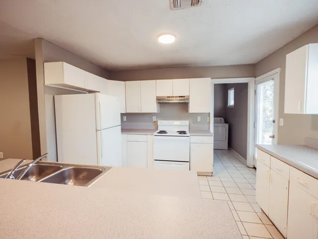 a kitchen with a sink white cabinets and white appliances