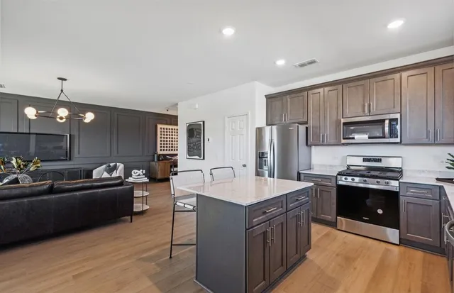 a kitchen with stainless steel appliances granite countertop a sink dishwasher stove and refrigerator with wooden floor