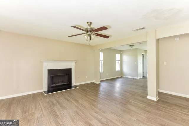 an empty room with wooden floor a ceiling fan and a fireplace