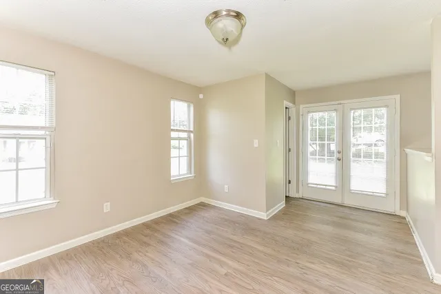 a view of an empty room with a window and wooden floor