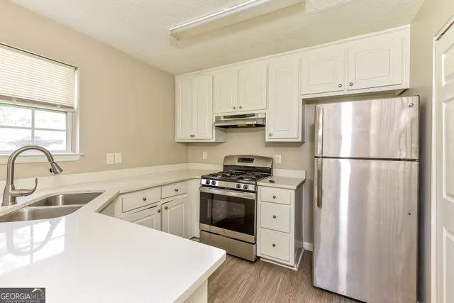 a kitchen with appliances a sink cabinets and a window