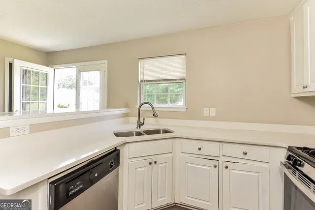 a kitchen with white cabinets and a window