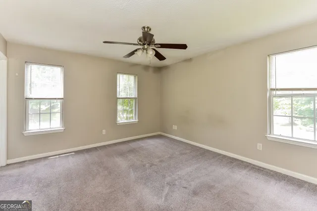 an empty room with windows and fan