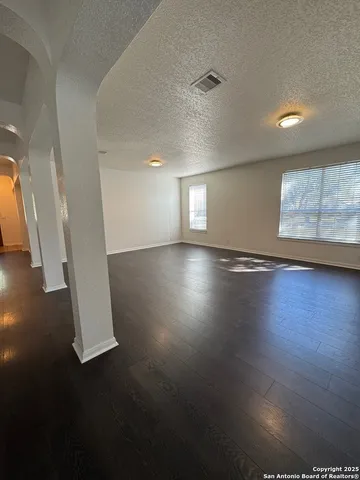 an empty room with wooden floor fan and windows