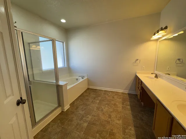 a spacious bathroom with a double vanity sink a large mirror and a bathtub