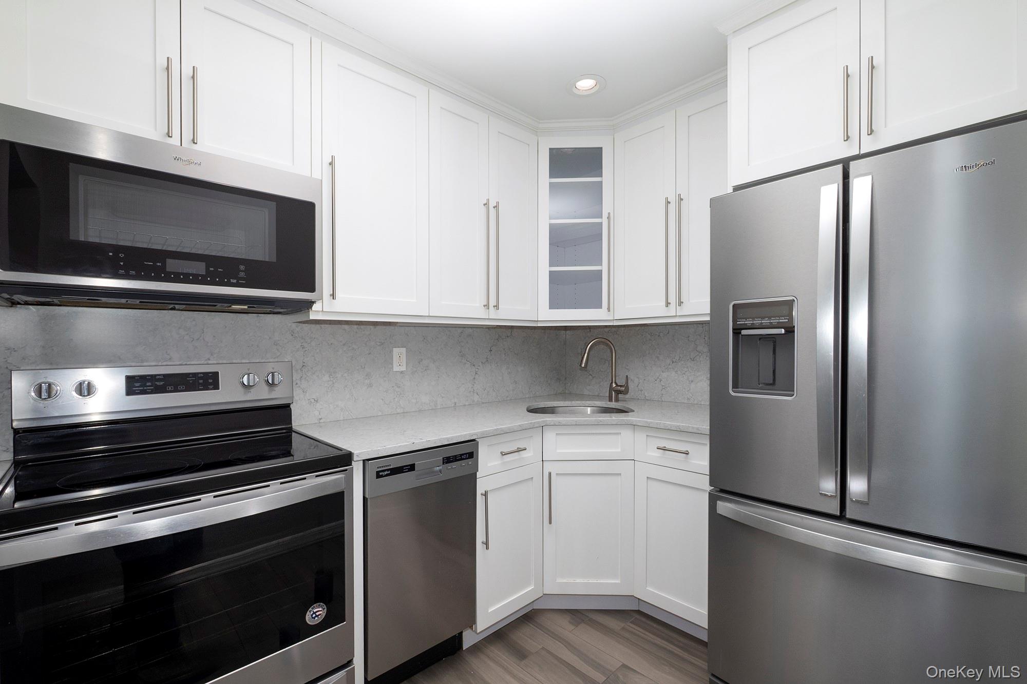 425 Newbridge Road, Unit 28 East Meadow, NY 11554 - Photo 3 of 8 a kitchen with stainless steel appliances a refrigerator stove and microwave