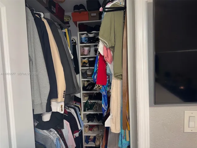 a view of walk in closet with clothes and shoes