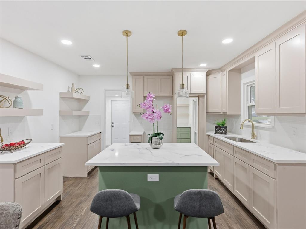 a kitchen with kitchen island granite countertop a sink cabinets and refrigerator