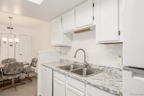 a kitchen with stainless steel appliances granite countertop a sink a stove and white cabinets