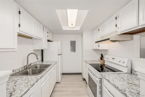 a kitchen with granite countertop a sink a stove and cabinets