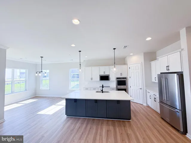 a large kitchen with a center island wooden floor stainless steel appliances and windows