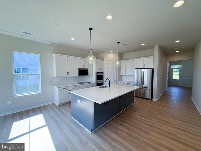 a large kitchen with stainless steel appliances a large center island wooden floor and a large window