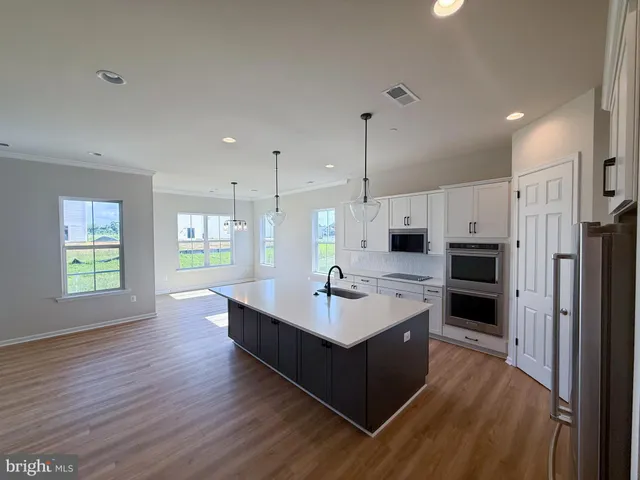a large room with kitchen island a sink wooden floor and a window
