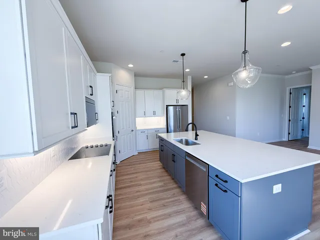 a large kitchen with kitchen island a stove a sink a center island and a wooden floor